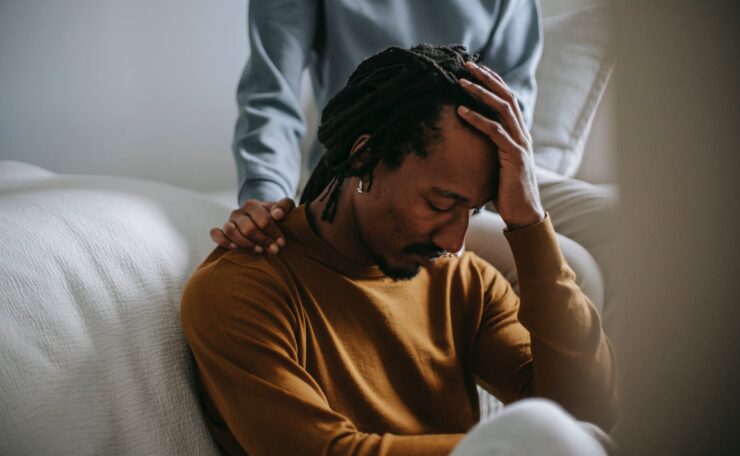 sorrowful black man touching head in dismay near supporting wife